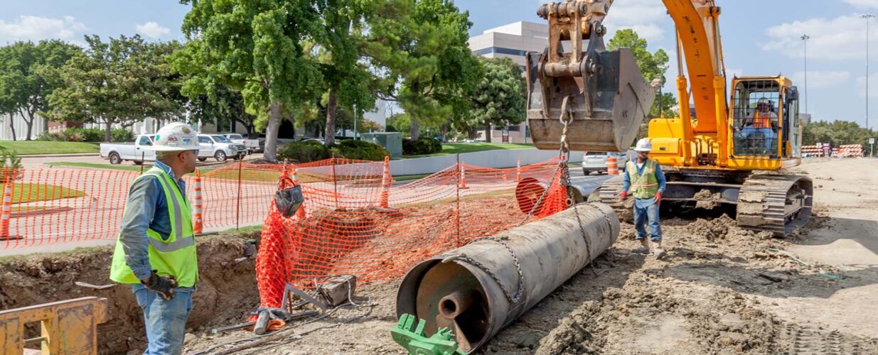 crew with excavator lifing pipe with chains at Rochelle Blvd